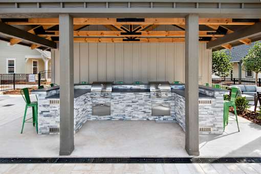 a covered patio with a barbecue grill and chairs at The Cottages at Old Monrovia Apartment , Huntsville, Alabama