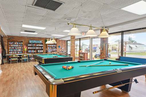 A pool table in a room with a brick wall and a bookshelf.