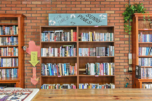 A room with a bookshelf and a sign that says "Fun Times Pines Sunny".