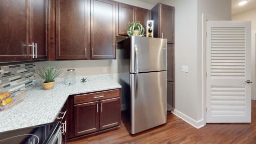 a kitchen with dark wood cabinets and white countertops at The Bend Arbordale, Williamsburg, 23188