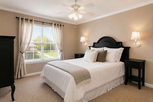 A bedroom with a large bed and a window with curtains.