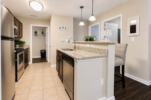 A kitchen with a granite counter top and stainless steel appliances.