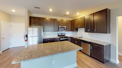 a kitchen with dark wood cabinets and an island with granite countertops at The Landing Apartment , Hazlet, NJ