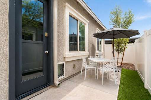 A patio with a table and chairs and an umbrella.