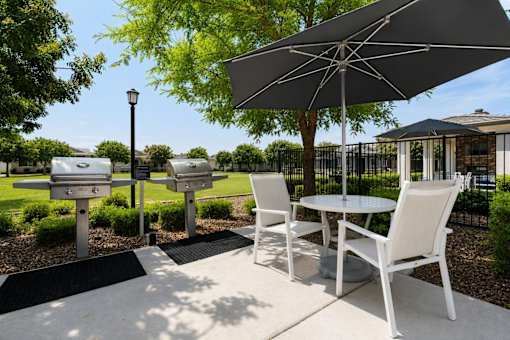A patio with a table, chairs and an umbrella.