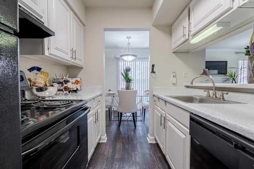A kitchen with black appliances and white cabinets. at 2400 Briarwest Apartments, Houston, TX