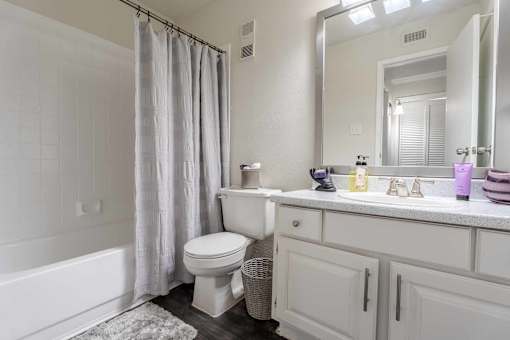 A white bathroom with a toilet, sink, and bathtub.at 2400 Briarwest Apartments, Houston, 77077