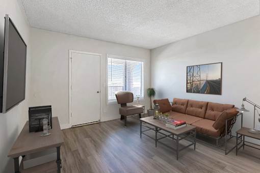 A living room with a brown couch, a coffee table, and a painting on the wall.