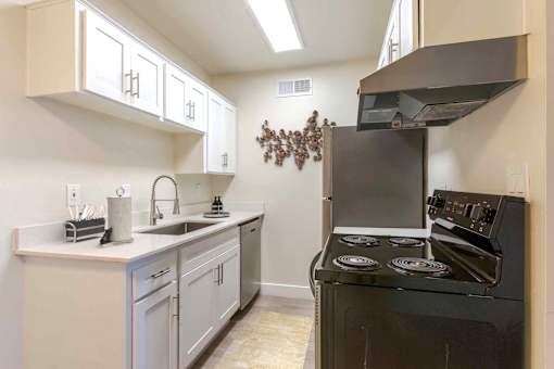 A kitchen with a black stove top oven and white cabinets.