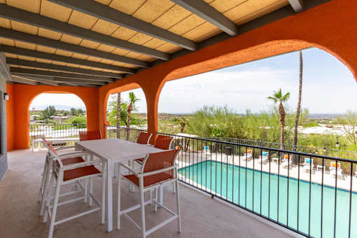A patio with a table and chairs overlooking a pool at Elevation Apartments, AZ