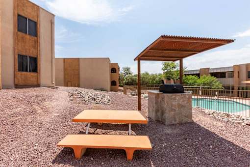 A picnic table is in front of a building with a pool at Elevation Apartments, AZ, 85718