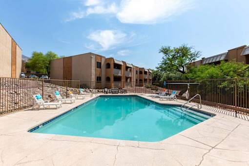 A swimming pool surrounded by a fence and chairs at Elevation Apartments, Tucson, AZ,85718