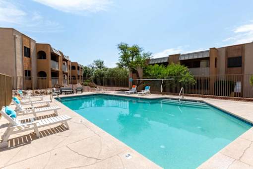A swimming pool surrounded by sun loungers and apartment buildings at Elevation Apartments, 85718