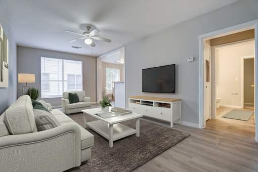 A living room with a white couch, a white coffee table, and a flat screen TV.