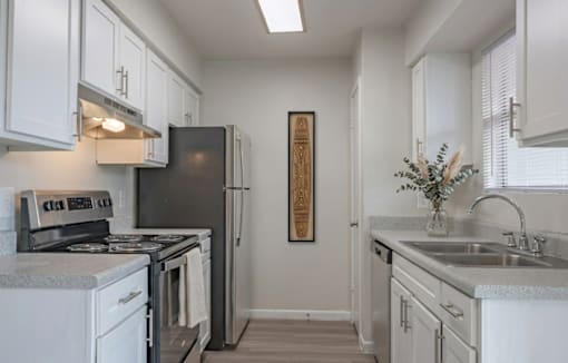 A kitchen with white cabinets and a black refrigerator.