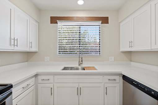 A kitchen with white cabinets and a window with blinds.at San Xavier Casitas, Tucson, AZ 85716
