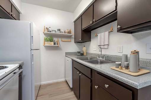 A small kitchen with a white refrigerator and brown cabinets.