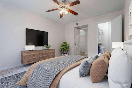 A bedroom with a bed, pillows, a ceiling fan, and a television on a wooden cabinet.