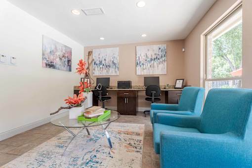 A living room with a blue chair and a glass table.