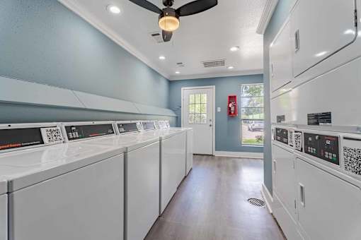 A laundry room with a row of washers and dryers.