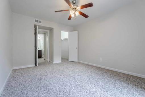 A room with a ceiling fan and carpeted floor.