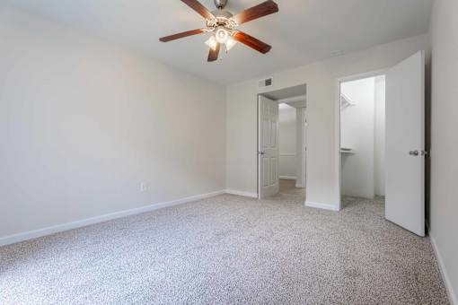 A room with a ceiling fan and carpeted floor.