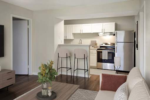 A modern kitchen with a refrigerator, stove, and bar stools.
