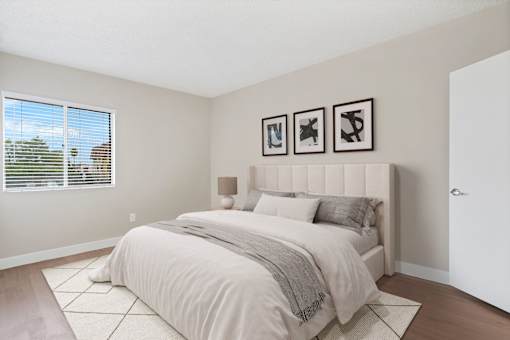 A bedroom with a large bed and three pictures on the wall.