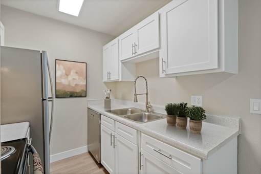 A kitchen with white cabinets and a refrigerator.