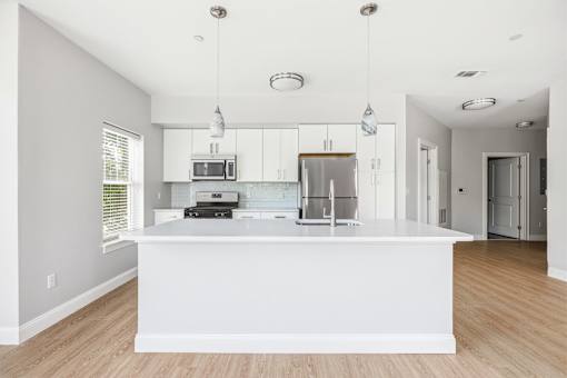 A modern kitchen with a white island and wooden floors.
