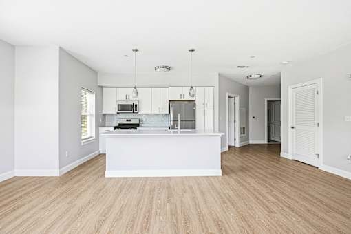 A kitchen with a white counter and wooden floors.