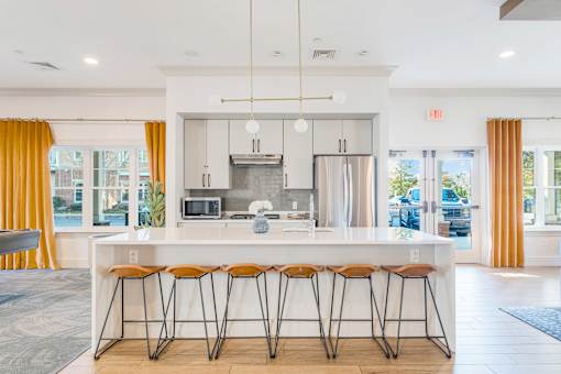 A modern kitchen with a white island and stools. at Axis at Lakeshore, Bridgewater, Massachusetts