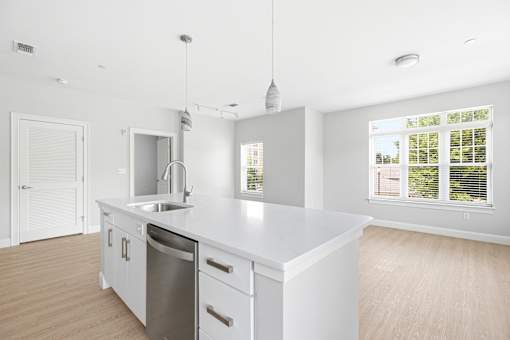 A white kitchen with a sink and a window.