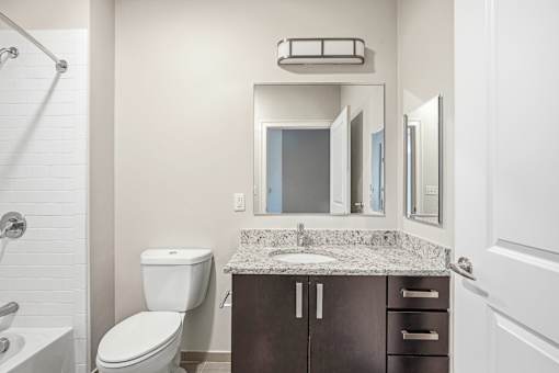 A bathroom with a toilet, sink, and mirror.
