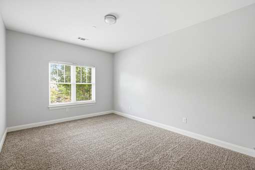 A room with a window and carpeted floor.
