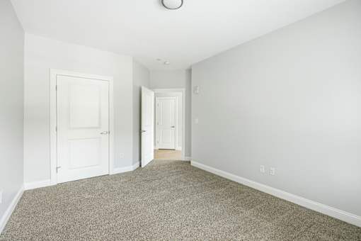 A room with a carpeted floor and two white doors.