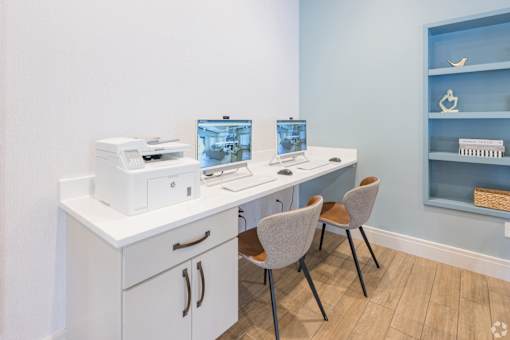 A white desk with a laptop and a printer on it.