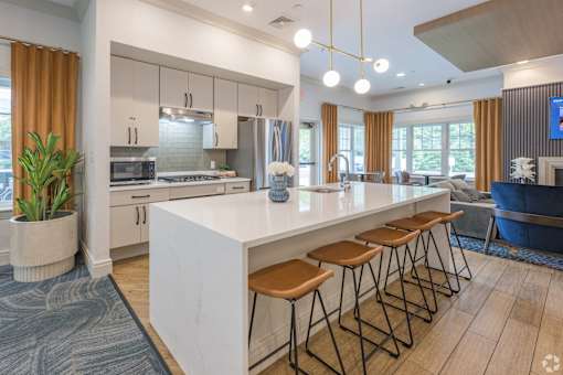 A modern kitchen with a white island and wooden stools.