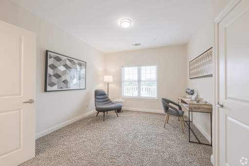 A room with a grey carpet and a chair.
