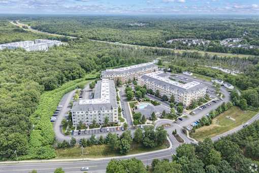 A large building complex surrounded by trees and a parking lot.
