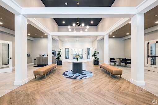 A spacious lobby with a wooden floor and white columns.