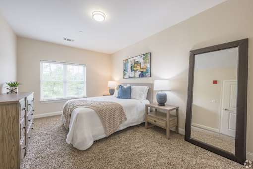 A bedroom with a bed, a nightstand, and a mirror.