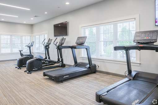 A gym with treadmills and a television mounted on the wall.