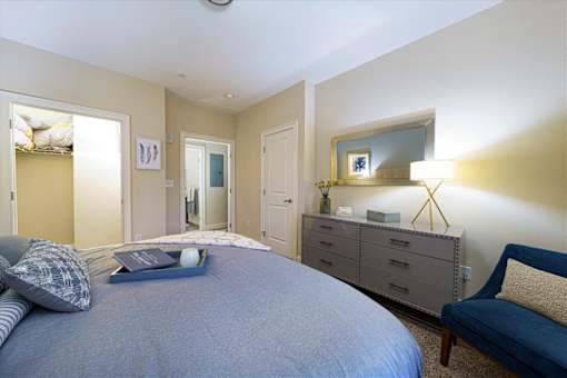 A bedroom with a bed, dresser, and mirror at Axis at Lakeshore Apartments, Massachusetts, 02324