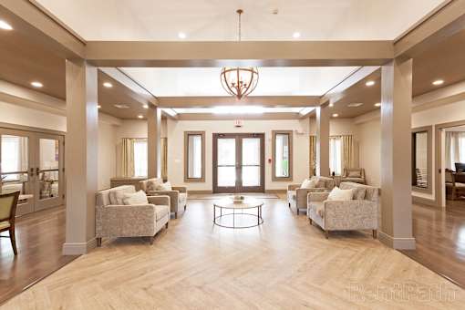 A spacious living room with a chandelier, couches, and a coffee table at Axis at Lakeshore Apartments, Bridgewater, MA