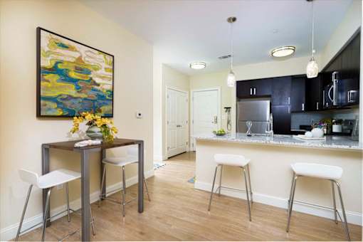 A kitchen with a bar and a painting on the wall at Axis at Lakeshore Apartments, Bridgewater, MA