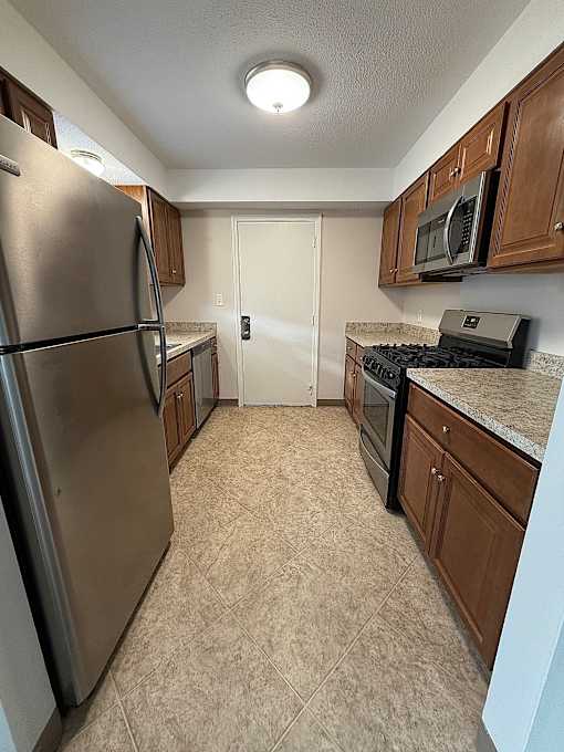 a kitchen with stainless steel appliances and wooden cabinets at Hidden Brook Apartment Homes Apartments, Massachusetts