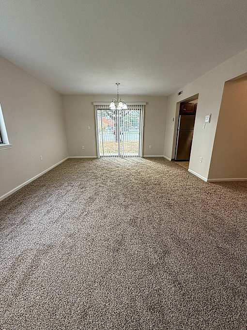 an empty living room with carpet and a door to a balcony at Hidden Brook Apartment Homes Apartments, New Bedford, 02740
