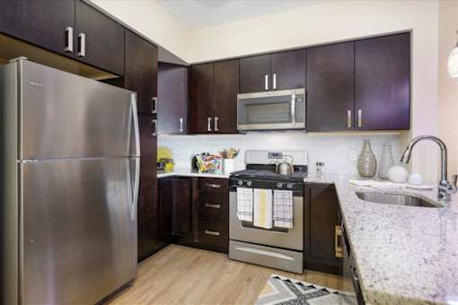 A kitchen with a stainless steel refrigerator, microwave, and oven at Axis at Lakeshore Apartments, Massachusetts