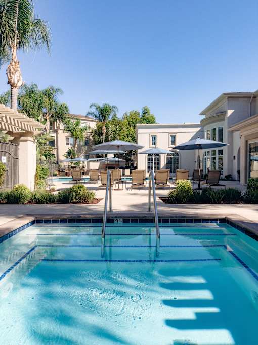 A spa and pool with a lounge chairs and umbrellas